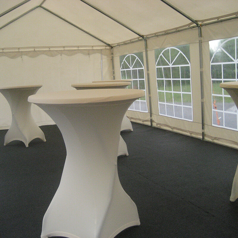 Intérieur d’une tente décorée avec des ballons blancs suspendus et des tables préparées pour un événement, avec des décorations florales.